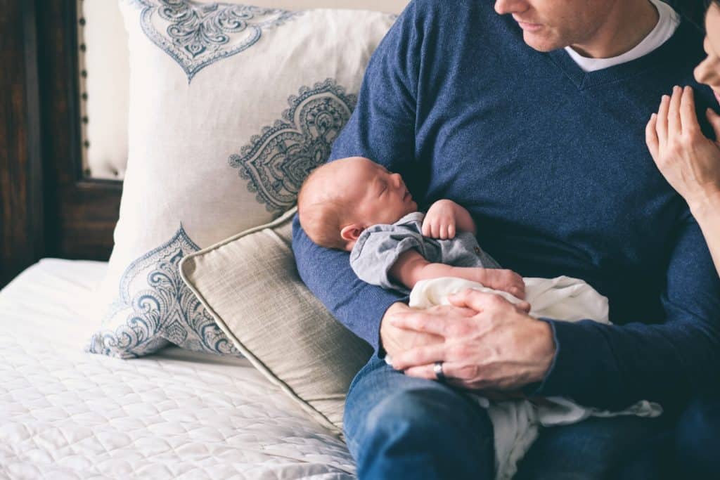[img] A man and woman holding a baby on a bed.