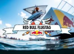 Red Bull Flugtag event banner featuring a human-powered flying craft soaring above water, the Red Bull logo in the background, and a lively community gathered to enjoy the spectacle.