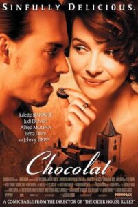 Movie poster for “Chocolat” showing a man and woman close together, with the woman holding a piece of chocolate—an intimate scene that echoes the allure and abundance found in Feeding The 5000. The tagline reads “Sinfully Delicious.” Cast and credits are listed at the bottom.