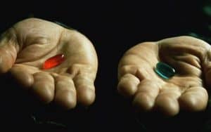 Two hands hold a red pill in the left palm and a blue pill in the right palm against a dark background, symbolizing the choices we face on our journey of spiritual growth and discovery.