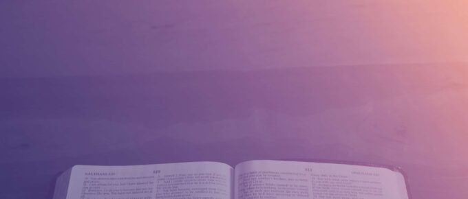 An open book, possibly a Bible, is placed on a flat surface with a purple and orange gradient light in the background, symbolizing spiritual growth through reflective Christian practices.