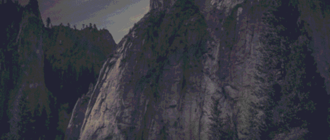 Towering granite cliffs, symbols of resilience, rise above a forest of evergreen trees.